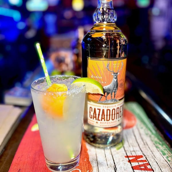 A margarita with lime and orange, next to a bottle of Cazadores Tequila Reposado.