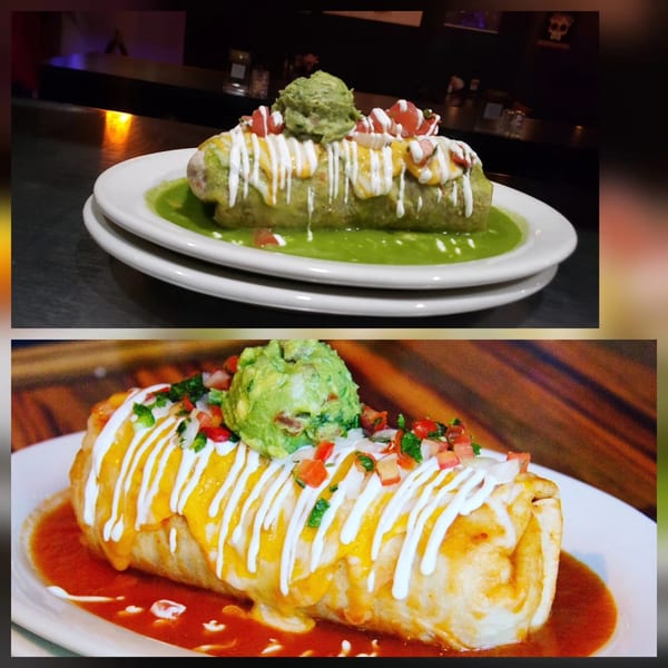 Two burritos, one with green sauce and one with red sauce, topped with guacamole and pico de gallo.